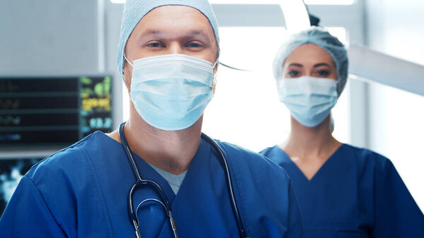 Professional medical doctors working in emergency medicine. Portrait of the surgeon and the nurse in protective masks performing surgical operation. Medical concept.
