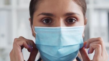 Hastane ofisinde profesyonel tıp doktoru koruyucu maskeli genç ve çekici bir kadın doktorun portresi. Tıbbi konsept.