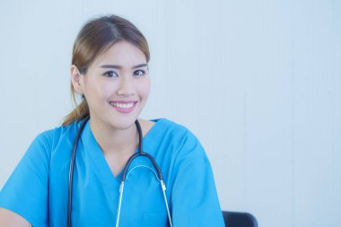 Üniformalı ve steteskoplu, gülümseyen bir yüzü olan Asyalı kadın doktor..