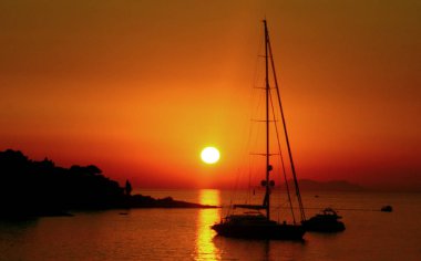 parlak kırmızı ve turuncu günbatımı Yelkenli tekne ile denizde güneşin arka planda ile