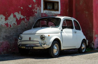 İtalya 'nın eski kasabasında küçük dar bir sokakta küçük beyaz bir araba duruyor.