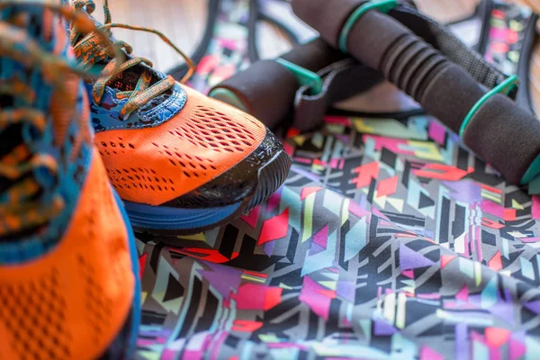 Running shoes with a colored tank top and dumbbells on wooden floor