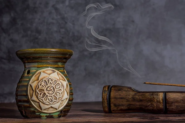 Essential oil burner with tibetan symbols and  incense on a grey stone background