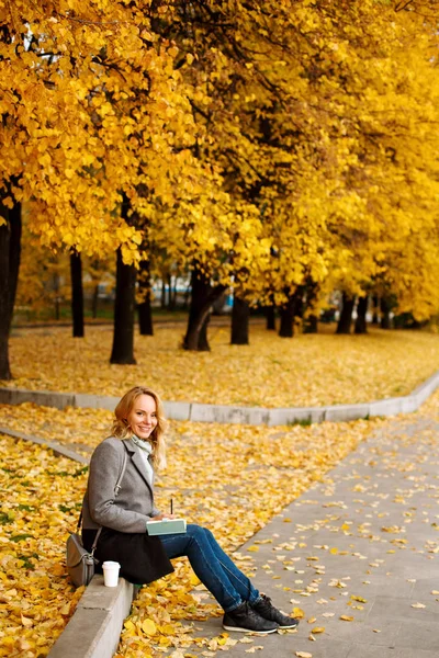 Vrouw zittend op een stoeprand en het schrijven van iets in haar noteboo — Stockfoto