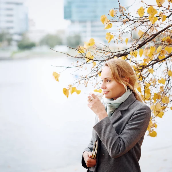 Jonge vrouw wandelen en drinken take-away koffie in de stad — Stockfoto