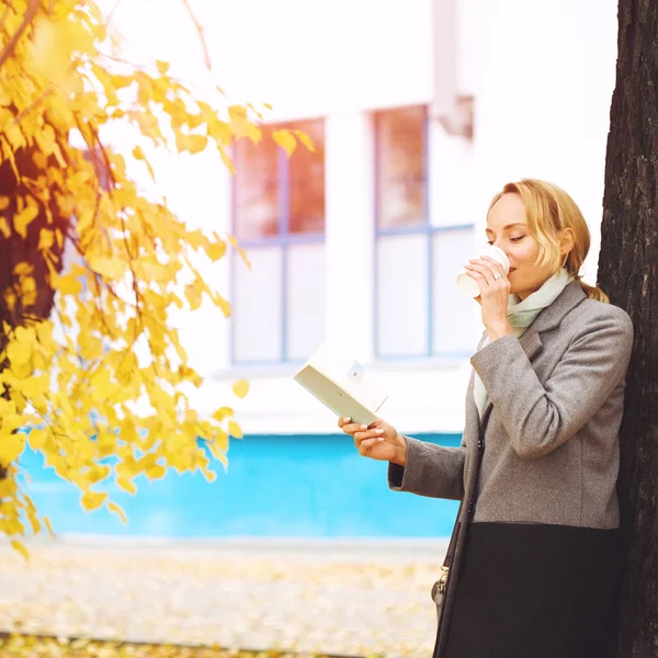 Creative woman in autumn park drinking coffee — Stock Photo, Image