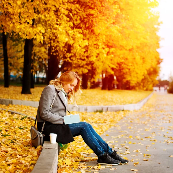 Woman sitting in autumn city park — Stock Photo, Image