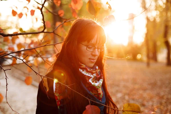 Nuori huomaavainen nainen seisoo puistossa auringonlaskun aikaan. — kuvapankkivalokuva