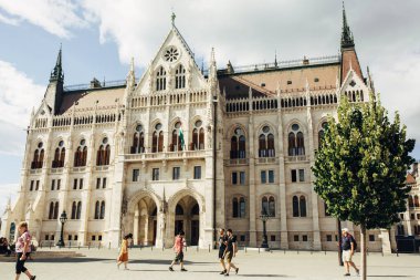 BUDAPEST, HUNGARY - 23 Temmuz 2019 - Macar parlamentosunun ünlü turistik mekanı, yaz günü önünde yürüyen turistlerle