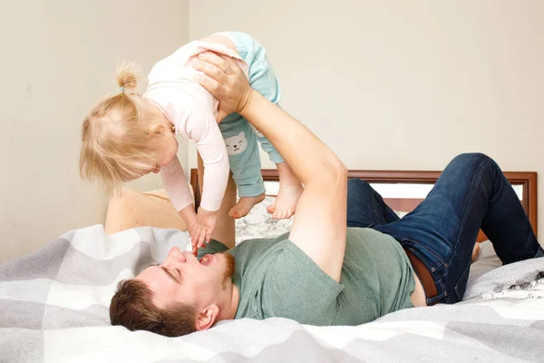 Ung Far Ligger Säng Och Håller Sin Dotter Barn Händerna — Stockfoto