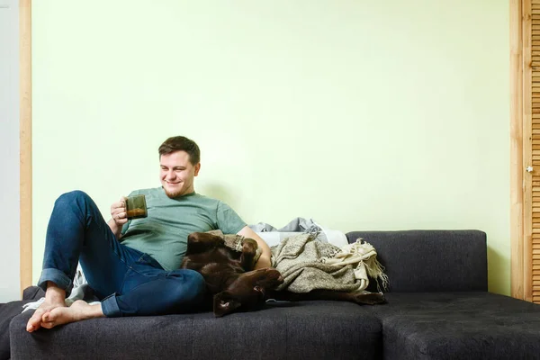 Pria Tampan Yang Duduk Sofa Rumah Dengan Anjing Peliharaan Labrador — Stok Foto