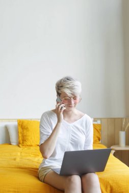 Pembe güneş gözlüklü, günlük kıyafetlerle cep telefonuyla konuşan son moda genç kadının yakın çekimi. 