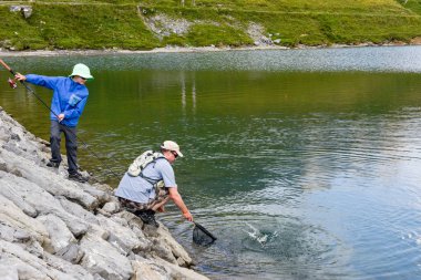 Tannensee, İsviçre - 4 Ağustos 2018: baba ve oğul birlikte, göl Tannensee İsviçre Alpleri üzerinde balık tutma