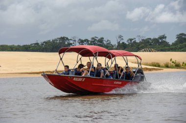Tourist boat travelling from Atins to Barreirinhas on river Preg clipart