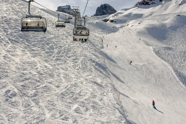 Gente esquiando y subiendo la montaña en telesilla en Engelber — Foto de Stock