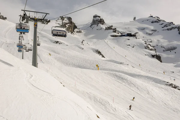 People skiing and going up the mountain by chairlift at Engelber — Stock Photo, Image