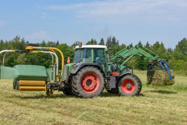 De'deki Vestbirk'te tarlada çalışan saman traktörü çiftçisi
