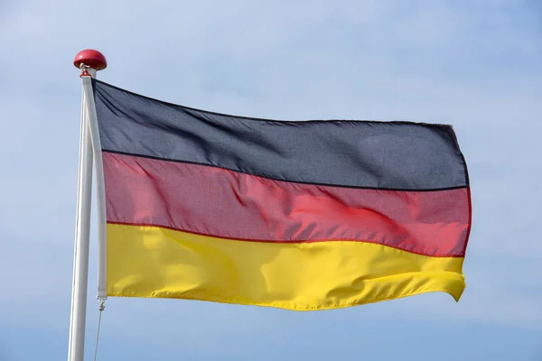Duitse vlag zwaaien tegen blauwe hemel — Stockfoto