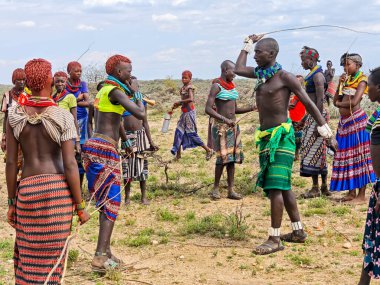 Dande, Etiyopya - 14 Ağustos 2025: kadın, Etiyopya yakınlarındaki Dande 'de düzenlenen boğa atlama töreninde onları kırbaçlaması için erkeği paketliyor.