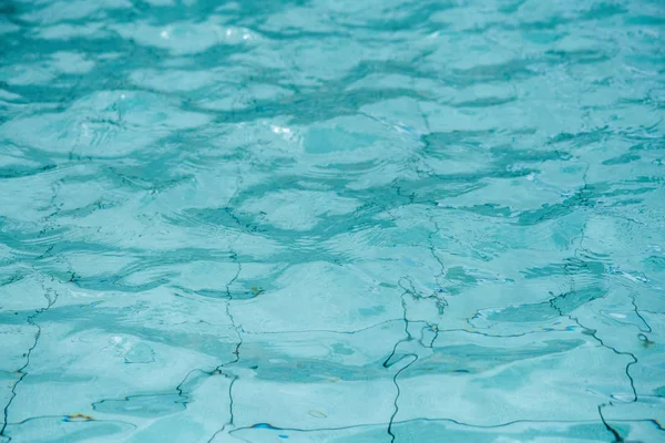 Mavi yüzme havuzunun yüzeyi. Yüzme havuzunda suyun arka planı.