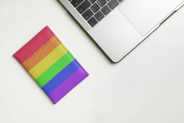 LGBT flag on passport, dildo and laptop on white desk with copy space. LGBT travel concept. Searching tickets online for dating. clipart