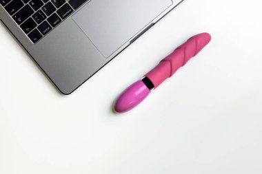 Yapay penis ve kopya alanı ile beyaz masa üstünde laptop. Rahat seks, karışıklık ve çok eşlilik kavramı için dating online.
