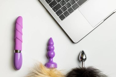 Yapay penis, anal plug kuyrukları ve beyaz Danışma laptop. Rahat seks, karışıklık ve çok eşlilik kavramı için dating online.