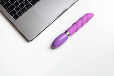 Yapay penis ve kopya alanı ile beyaz masa üstünde laptop. Rahat seks, karışıklık ve çok eşlilik kavramı için dating online.