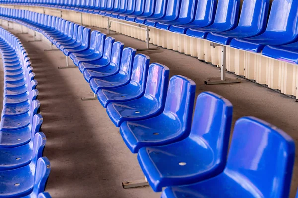 Blue stadium seats. Soccer, football or baseball stadium tribune without fans. End of the game.