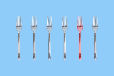 Altı parlak çatal gümüş ve kırmızı biri. İzole mavi arka plan. Kopya alanı.