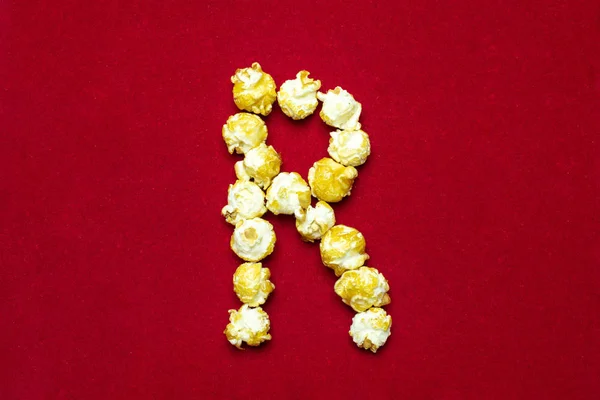 Английский алфавит из кинопопкорна. Буква R. Красный фон f — стоковое фото