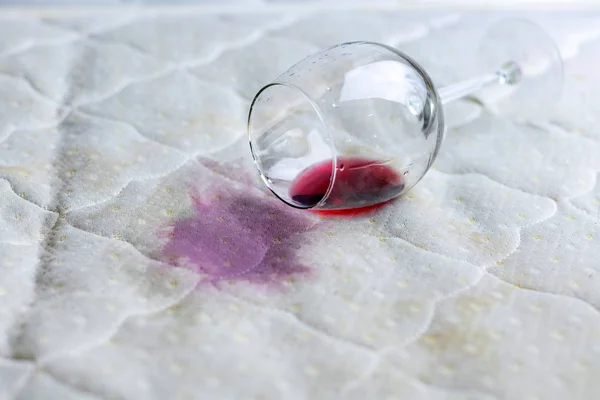 Copo de vinho derramado na cama. Vinho acidentalmente caído em — Fotografia de Stock