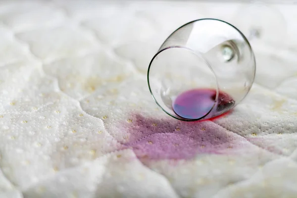 Copo de vinho derramado na cama. Vinho acidentalmente caído em — Fotografia de Stock