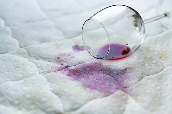 Copo de vinho derramado na cama. Vinho acidentalmente caído em — Fotografia de Stock