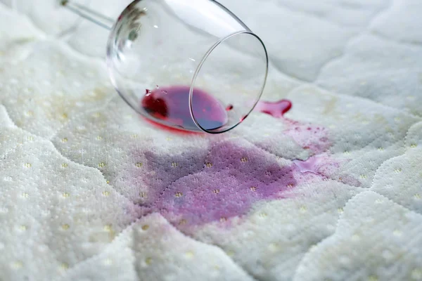 Copo de vinho derramado na cama. Vinho caído em lençol branco . — Fotografia de Stock