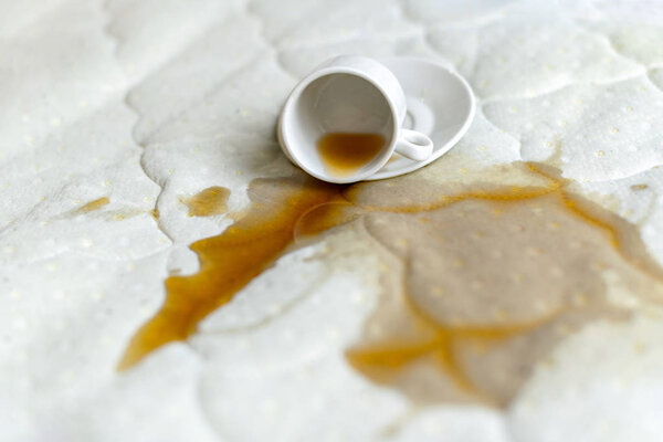 Spilled cup of tea on the bed. Accidentally dropped cup with sau
