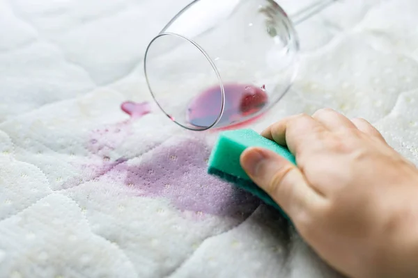 Limpar a mancha de vinho com esponja. Vinho derramado em lençol branco — Fotografia de Stock