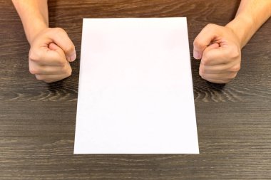 Masada oturan işadamı. Masada boş bir kağıt var. Elleriyle öfkeli jest. Konsept fotoğraf.