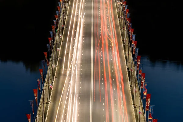 Nizhniy Novgorod / Rússia - 06.16.2018: Ponte rodoviária através do rio. Auto-estrada com faixas de luz do carro. Fotografia de longa exposição . — Fotografia de Stock