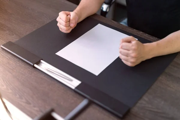 Empresário sentado à mesa. Há uma folha de papel em branco na mesa. Um gesto de raiva com as mãos. Fotografia de conceito . — Fotografia de Stock