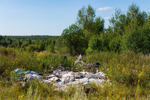 Unauthorized garbage dump in the summer field.