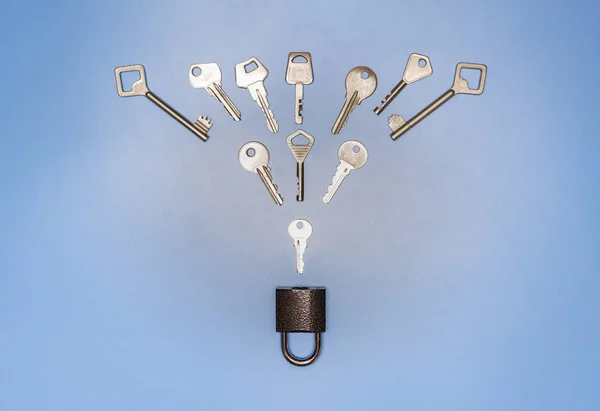 Key picking concept. Lock and different antique and new keys, blue background. Protection of business and house, real estate security.