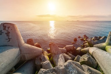 Güzel gün batımı deniz manzarası. Kırık sular tetrapodlar iskele nin kıyısına. Kargo gemileri ufukta. Seyahat hayalleri ve motivasyon