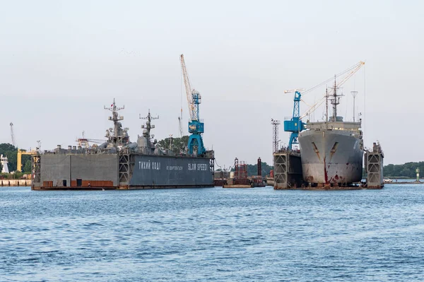 Grandes navios da marinha de ferro no estaleiro para reparação. Um grande guindaste no estaleiro. Porto marítimo azul — Fotografia de Stock