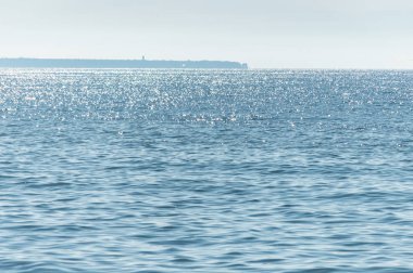 Güneşli deniz manzarası. Uzakta yarımadanın bir parçası. Sakin ve güzel hava. Rüzgar yok
