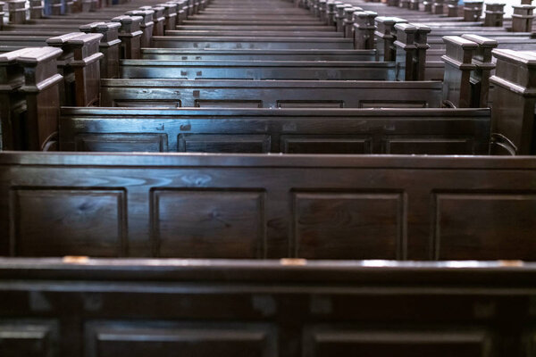 Cathedral pews. Rows of benches in christian church. Heavy solid uncomfortable wooden seats.