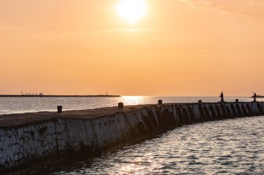 Baltık rıhtımı üzerinde deniz gün batımı. Seyahat ve özgürlük hayalleri. Güzel iskele deniz manzarası. Günbatımı gökyüzü ve iddia hava.