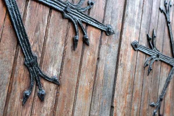 Выкованный узор на двери с декоративными элементами. Старый винтажный вход, массивные тяжелые деревянные двери церкви или собора . — стоковое фото