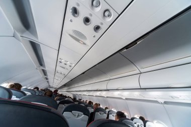 Koltuklar üzerinde uçak klima kontrol paneli. İnsanlarla uçak kabininde hava sızılı hava. Yeni düşük maliyetli havayolu
