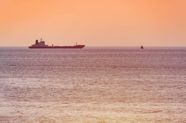 Küçük römorkör ve büyük kargo gemisi. Deniz üzerinde güzel gün batımı. Nefes kesen seyahat görünümü, kopyalama alanı.
